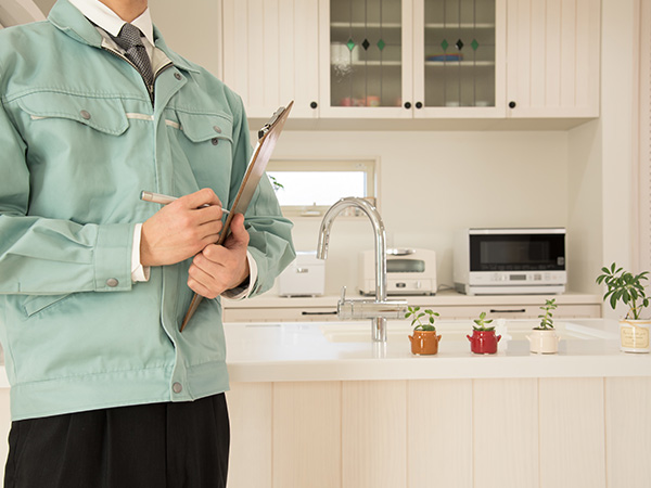 man in a green jacket holding a clipboard in a modern kitchen with small plants on the counter home inspection kitchen design