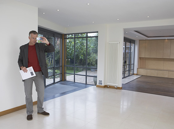 man taking a photo in modern living space showcasing two large windows and an open area ideal for home improvement and design