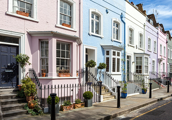 colorful row of houses with pastel pink and blue exteriors showcasing charming architecture and potted plants in a sunny urban setting with three distinct colors